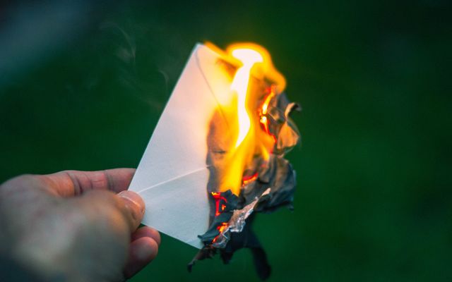 Mano sosteniendo una carta ardiendo
