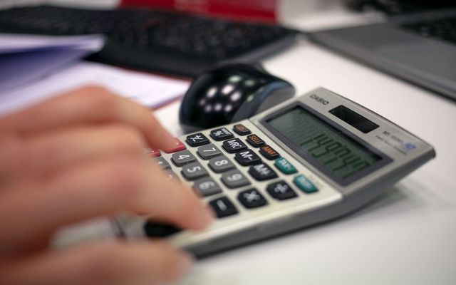 Mano usando una calculadora junto a documentos