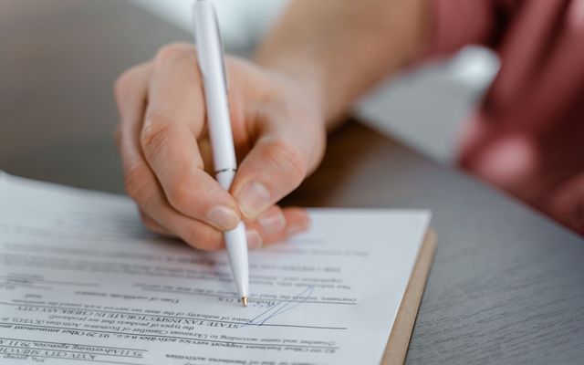 Mano escribiendo con lápiz sobre un documento